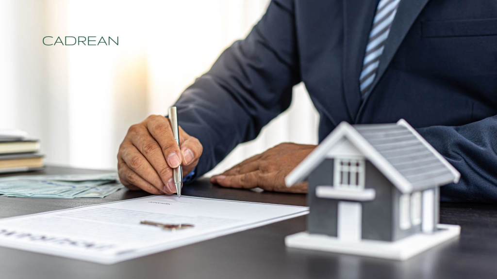 Male person signing a contract with the model of a house on the desk in front.